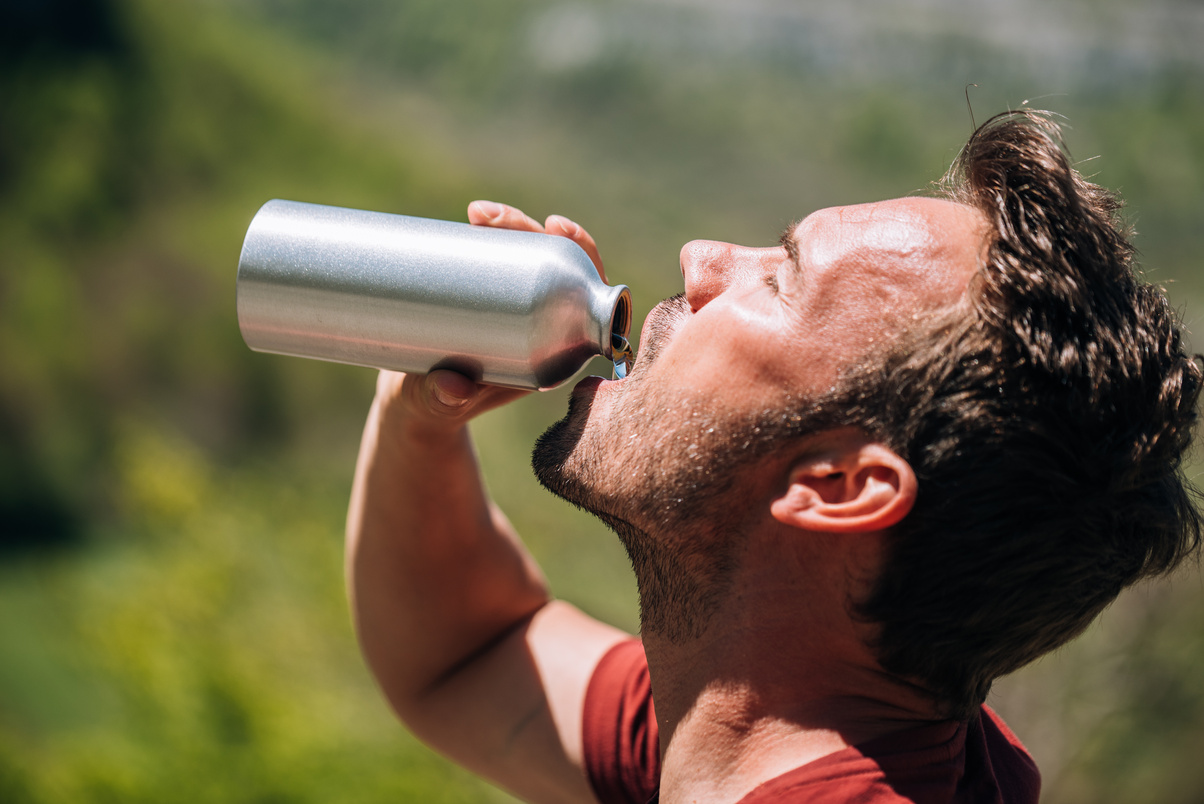 Thirsty man drinking water from reusable bottle